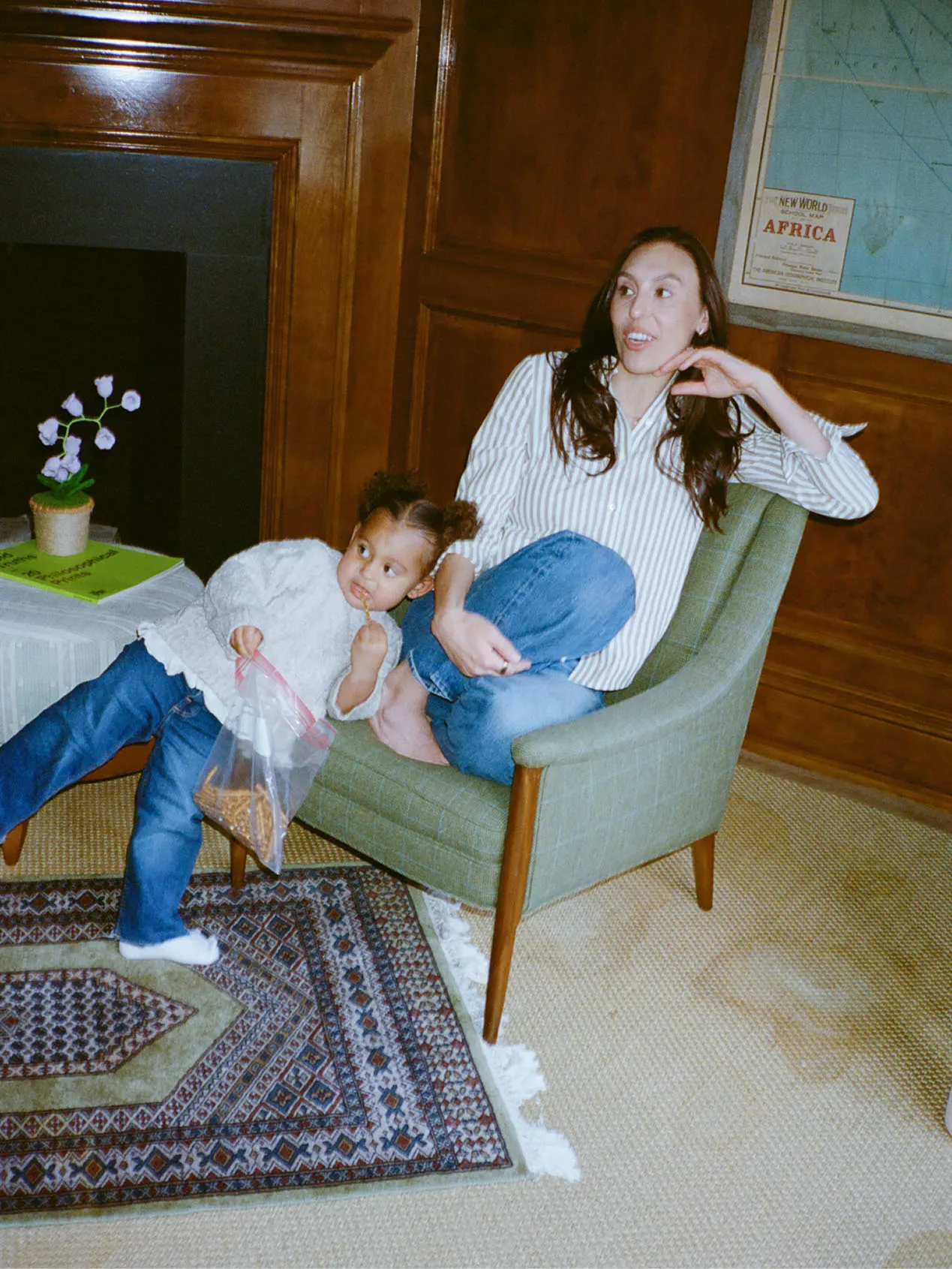 Dr. Sara Bloom, founder of Mavie, sitting in a chair with her young child leaning beside her in a cozy room.